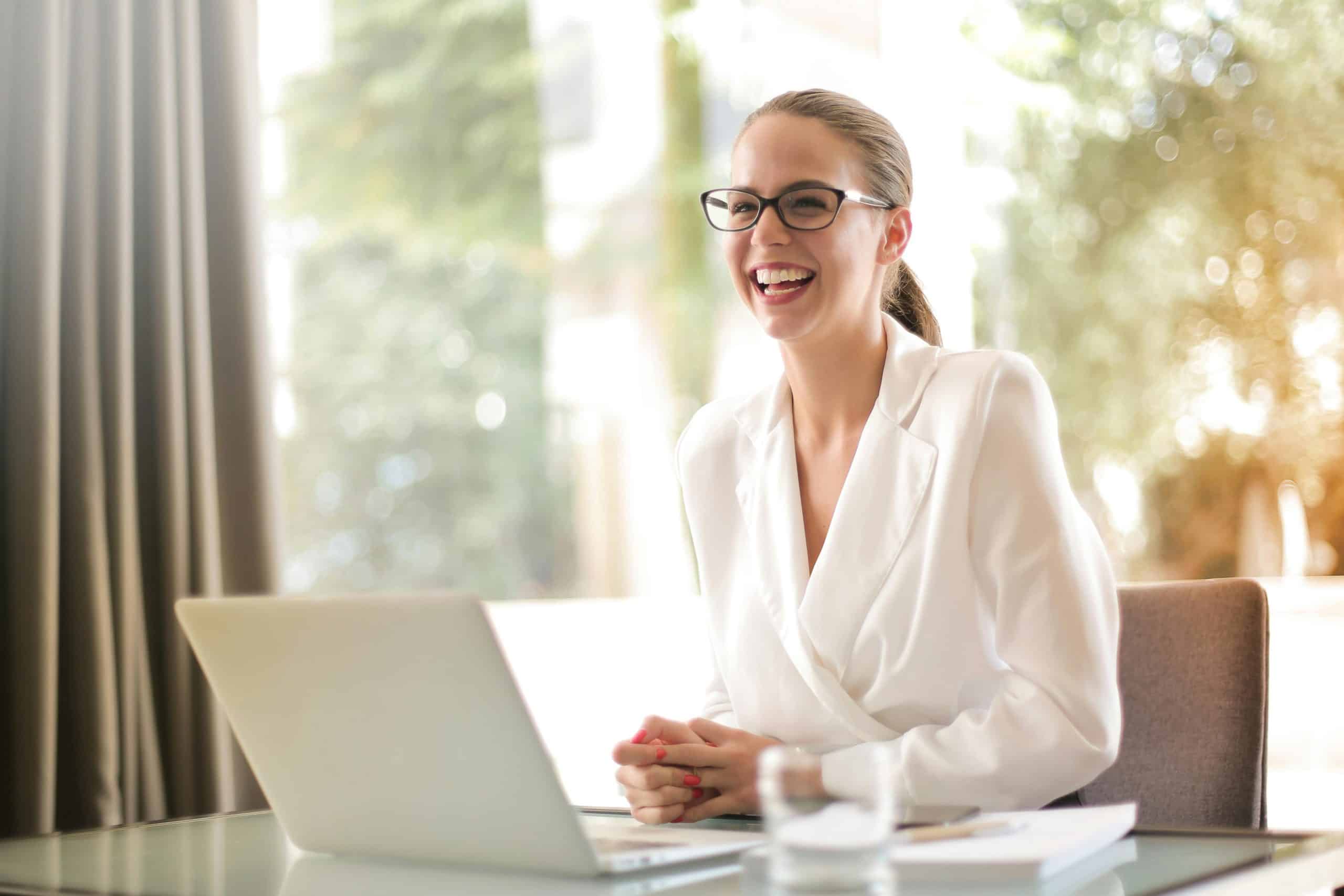 A person sitting at a desk in a bright office, smiling at their laptop after receiving support through Automated Care Pathways.